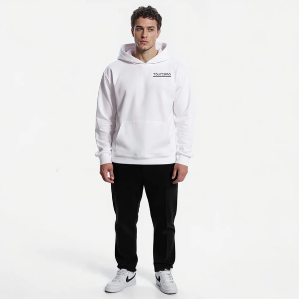 Sweat blanc pour homme avec logo noir Tourismo, pantalon noir classique, baskets Nike blanches. Look minimaliste et contrasté, modèle face caméra, bras le long du corps, fond blanc épuré.