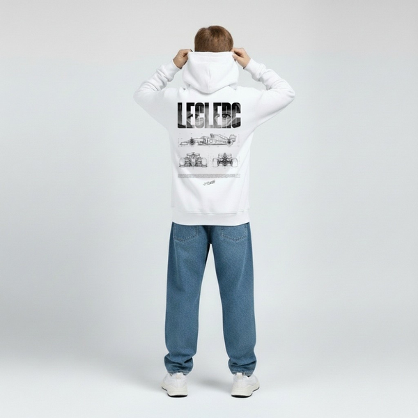 Enfant vu de dos portant le hoodie blanc Charles Leclerc, visuel paddock imprimé en noir avec nom typographié, tracé de circuit et numéro signature. Capuche posée, jeans bleus, fond studio gris clair.