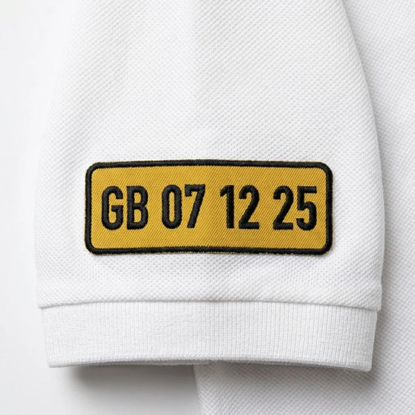 Gros plan sur la plaque GB 07 12 25 brodée sur la manche du polo blanc